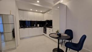a kitchen with a table and two blue chairs at Sapphire Suite #pool&parking #Cosmopolis in Ştefăneştii de Sus