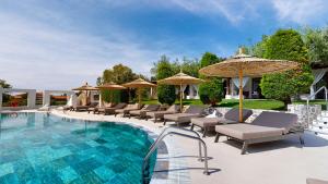una piscina con lettini e ombrelloni di Acrotel Athena Pallas & Residence a Elia