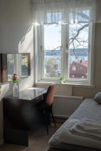 een slaapkamer met een bureau voor twee ramen bij STF Sigtuna Vandrarhem in Sigtuna