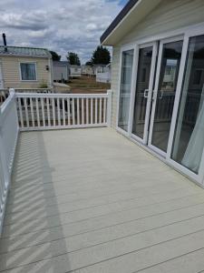 a deck with a white fence and a house at Life is Adventure in Great Clacton