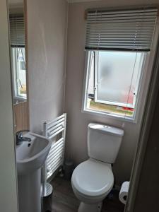 a bathroom with a toilet and a sink and a window at Life is Adventure in Great Clacton +4 photos