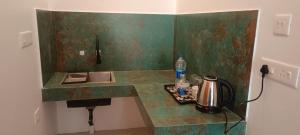 a kitchen with a green counter top with a tea kettle at tippys beach resort in Kovalam