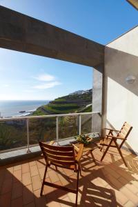 einen Balkon mit 2 Stühlen und einem Tisch sowie Meerblick in der Unterkunft Hotel Escola in Funchal