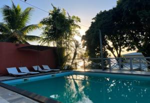 a swimming pool with chairs and an umbrella at La Colombine Appart'Hôtel in Sainte Marie