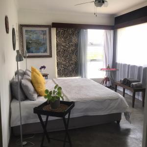 a bedroom with a bed and a table and a window at 120 steps to the beach in Pringle Bay