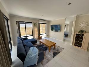 a living room with a blue couch and a table at Ocean Whisper in Wannanup