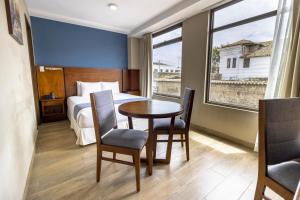een hotelkamer met een bed, een tafel en stoelen bij Hotel San Agustin Plaza in Latacunga