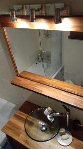 a bathroom sink under a wooden shelf with a faucet at LePré Apartment 93 in Le Pré-Saint-Gervais