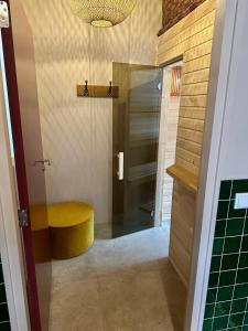 un bagno con uno sgabello giallo e una doccia di Unieke Yurt in het bos met jacuzzi en sauna a Erp Altre 37 foto