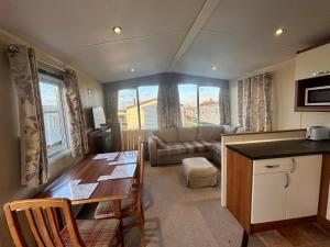 a kitchen and living room with a table and a couch at Relax By The Coast - Spacious 6-sleeper Caravan in Leysdown-on-Sea
