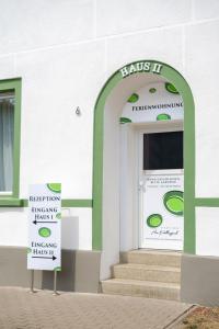 a white building with a door with a sign in front at Pension am Pollingpark Haus II in Dessau