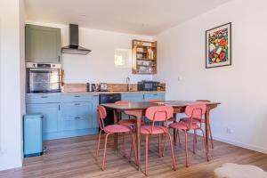 a kitchen with a wooden table and pink chairs at La Garencière - Les Fleurs in Champfleur