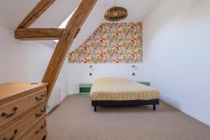 a attic bedroom with a bed and a window at La Garencière - Les Fleurs in Champfleur