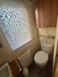 a small bathroom with a toilet and a window at Relax By The Coast - Spacious 6-sleeper Caravan in Leysdown-on-Sea +10 photos