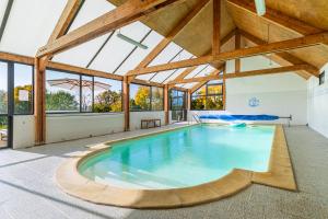 an indoor swimming pool in a building with wooden ceilings at La Garencière - Les Fleurs in Champfleur
