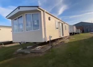 a tiny house is sitting in a yard at Relax By The Coast - Spacious 6-sleeper Caravan in Leysdown-on-Sea