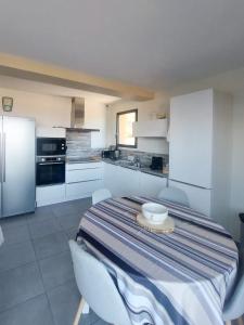 a kitchen with a table and chairs and a kitchen with white cabinets at Résidence Le Vénusia - 2 in Port-Vendres +6 photos