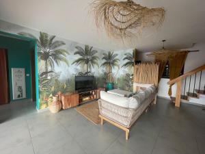 a living room with a couch and a tv and palm trees at Villa Exotiqua Sunset in La Saline les Bains