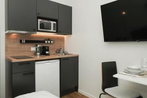 a kitchen with black cabinets and a microwave at Stylish smart studio in Tallinn