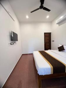 een slaapkamer met een bed en een flatscreen-tv bij VVR Residency in Kuilapayam