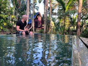 a man sitting on the edge of a pool of water at Brooklyne Jungle Nest in Udawalawe
