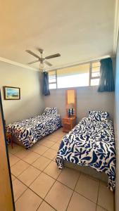 a bedroom with two beds and a ceiling fan at L’Escalier Cabanas 510 in Amanzimtoti