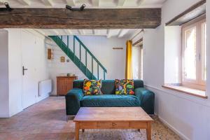 a living room with a green couch and a table at La Garencière - La Petite Maison in Champfleur +19 photos