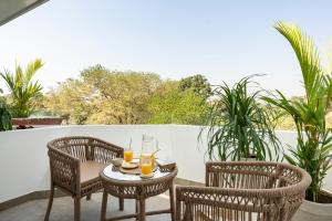 two chairs and a table with two glasses of orange juice at El Volar by The Blue Kite - 2BHK, 5 Mins to Casino & 10 Mins to Candolim Beach with Big common Pool, Fully Equipped Kitchen, 24x7 Security, WiFi in Nerul