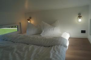 a bed with white sheets and pillows in a room at Tiny House Auszeit in Nabegg