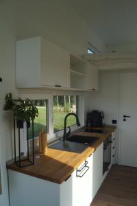 a kitchen with white cabinets and a sink and a counter at Tiny House Auszeit in Nabegg