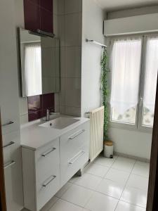 a white bathroom with a sink and a window at La Pause Normande - Bed & Breakfast in Bayeux