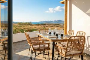 a table and chairs on a balcony with a view of the ocean at Kyma Paros Sea View Luxe Suite in Paros National Airport
