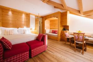 un dormitorio con una cama grande y un sofá rojo en Maribel Hotel, en Madonna di Campiglio 105 fotos más