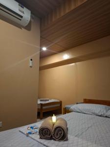 a room with two beds with towels and a candle at Queenbee's Place in Tagum