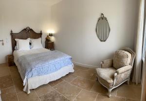 a bedroom with a bed and a chair and a mirror at Les Chantours, Domaine naturel arboré et fleuri de15 hectares in Saint-Antoine-Cumond
