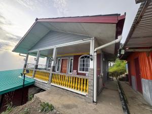 a house with a porch with a yellow railing at ff HILLTOP VIEW in Kampong Kundassan