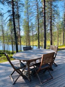 een houten tafel en stoelen op een terras met een meer bij Villa Havu in Kuusamo