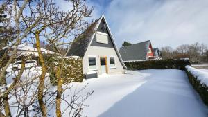 a house with a snow covered yard with a church at Harzer Finnhütte in Elbingerode