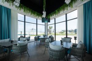 a restaurant with tables and chairs and large windows at CaspiMayr Retreat Beach Resort in Baku