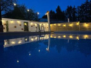a swimming pool at night with lights on a fence at Gîte Baytso in Auge