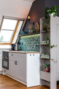 a kitchen with white cabinets and a brick wall at Complete studio de Stopplaats dichtbij Hoorn en Alkmaar in Zuidermeer
