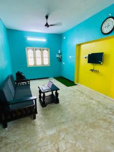een kamer met een bank en een klok aan een muur bij Butterfly Blossom Villa in Samayapuram