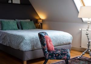 a bedroom with a bed with a chair next to it at Complete studio de Stopplaats dichtbij Hoorn en Alkmaar in Zuidermeer