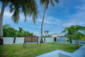a park bench in a yard with palm trees at The Urban Stay in Galle
