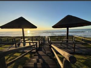 a group of benches with umbrellas on the beach at Condomínio Morada do sol in Barra Velha