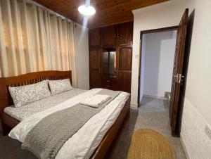 a bedroom with a large bed with a wooden headboard at Toiwo Residence Arusha in Arusha