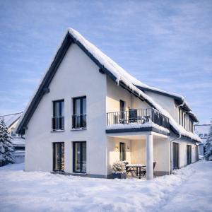 una casa bianca con la neve sul tetto di WeberHof Appartements a Burg