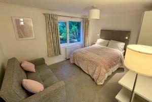a bedroom with a bed and a couch and a window at Oaktree Cottage, overlooking Loch Fyne in Cairndow