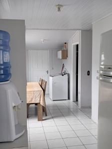 a white kitchen with a table and a refrigerator at Oásis Xangri-lá in Xangri-lá