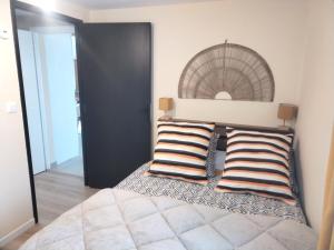 a bedroom with a bed with two striped pillows at Logement proche du Lac & Océan, Parking in La Chevrolière